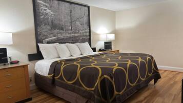 A hotel room with a large bed, a nightstand with a lamp, a dresser, and a painting on the wall.