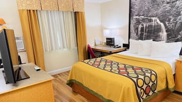 Une chambre d’hôtel avec un lit, un bureau équipé d’un ordinateur, une télévision et un grand tableau encadré au mur.
