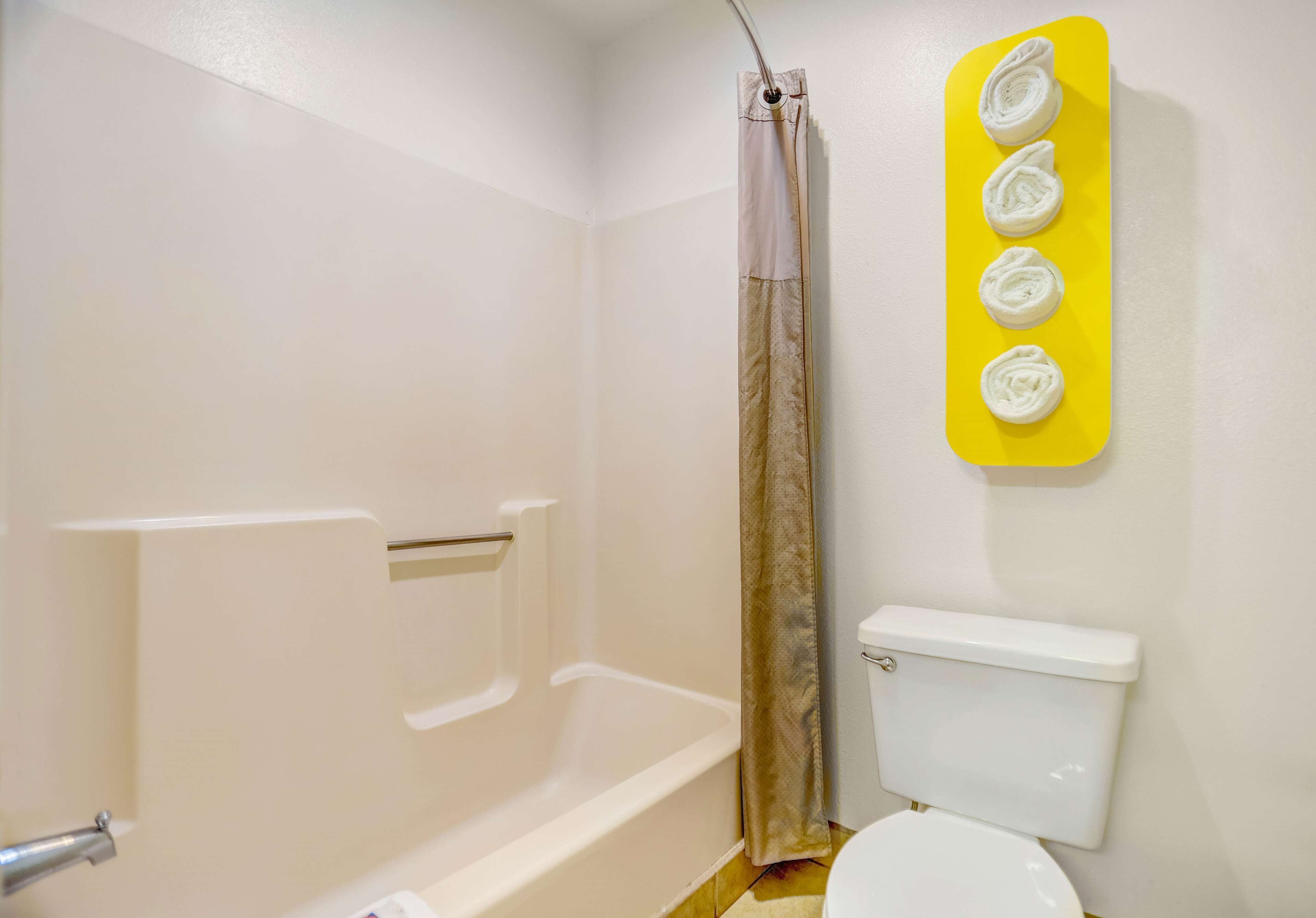 Et badeværelse med badekar, toilet og bruseforhæng.