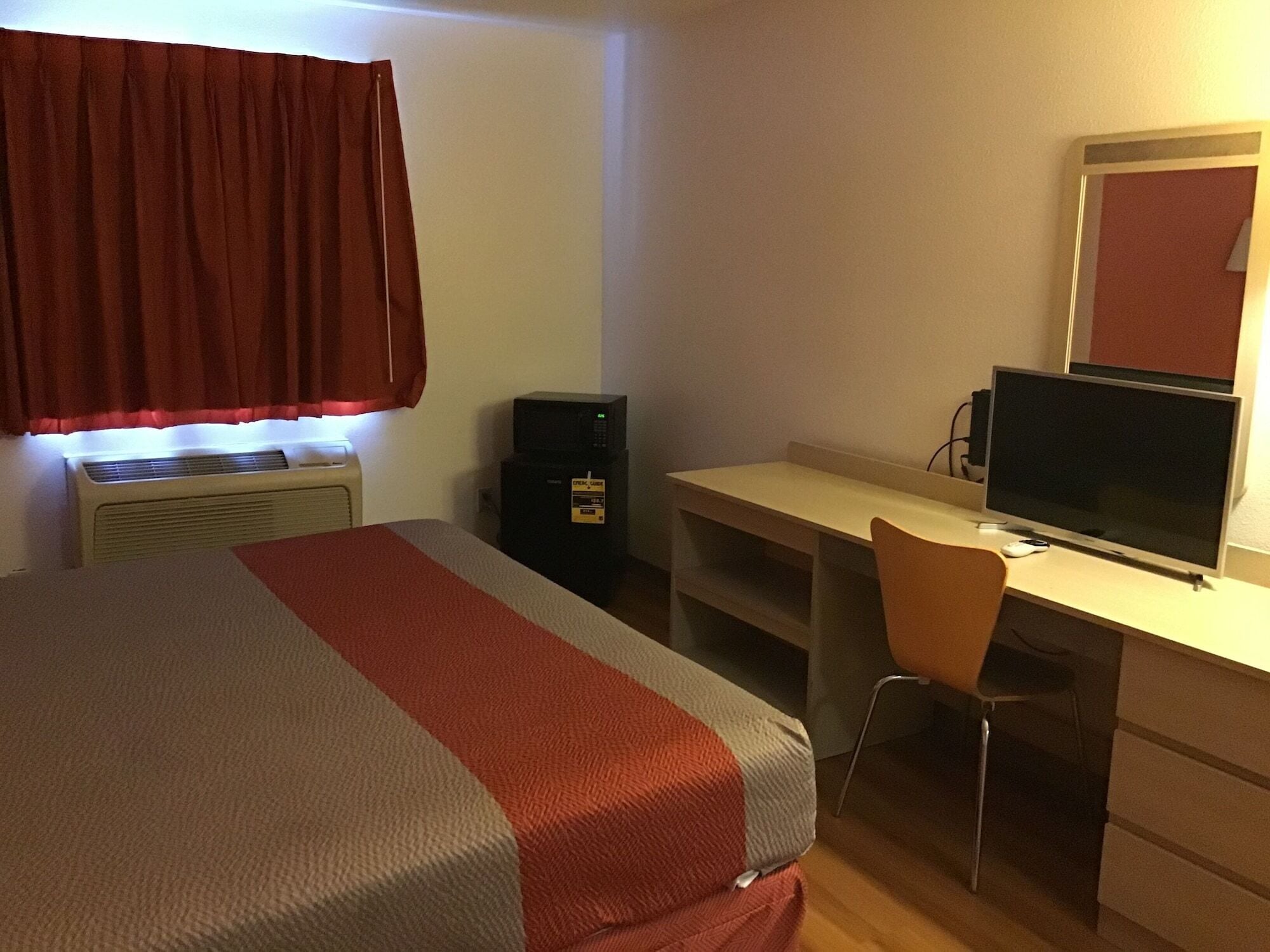 Une chambre d’hôtel comprenant un lit, un bureau avec un ordinateur et un écran, une chaise, un radiateur et une armoire.