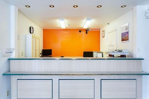 Uma área de recepção com balcão, relógio e mural de avisos.