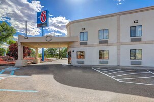 Um motel com um letreiro grande, área de estacionamento coberta e um edifício com várias janelas.