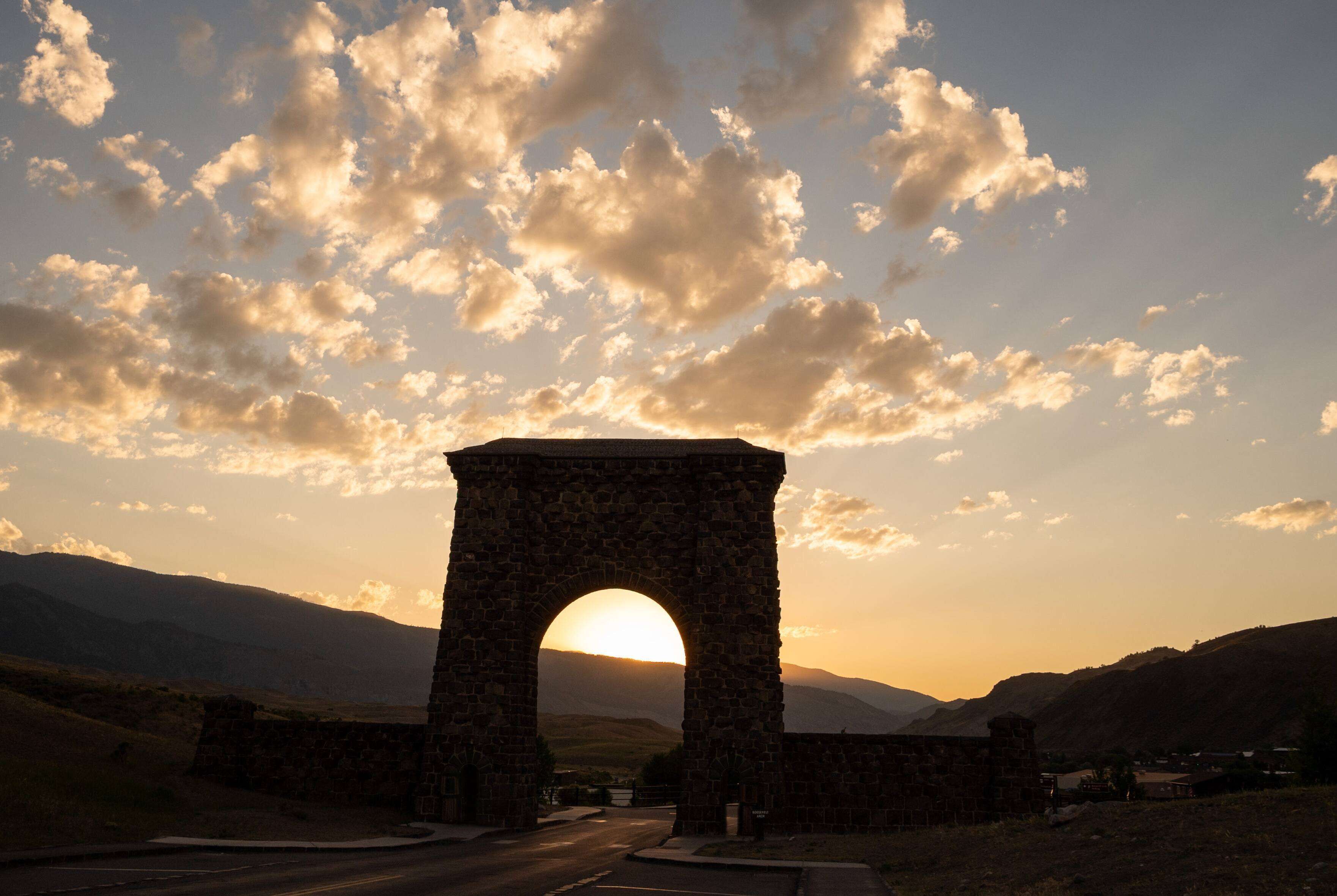 A stone archway with a sunset in the background.