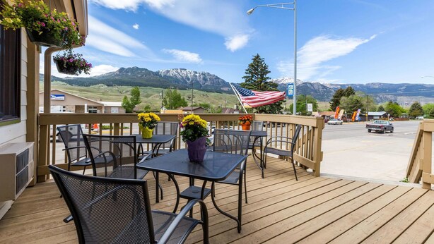 A wooden deck with outdoor seating, a view of mountains, and an American flag.