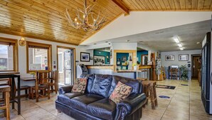 A spacious living area with a leather sofa, wooden furniture, and a chandelier.