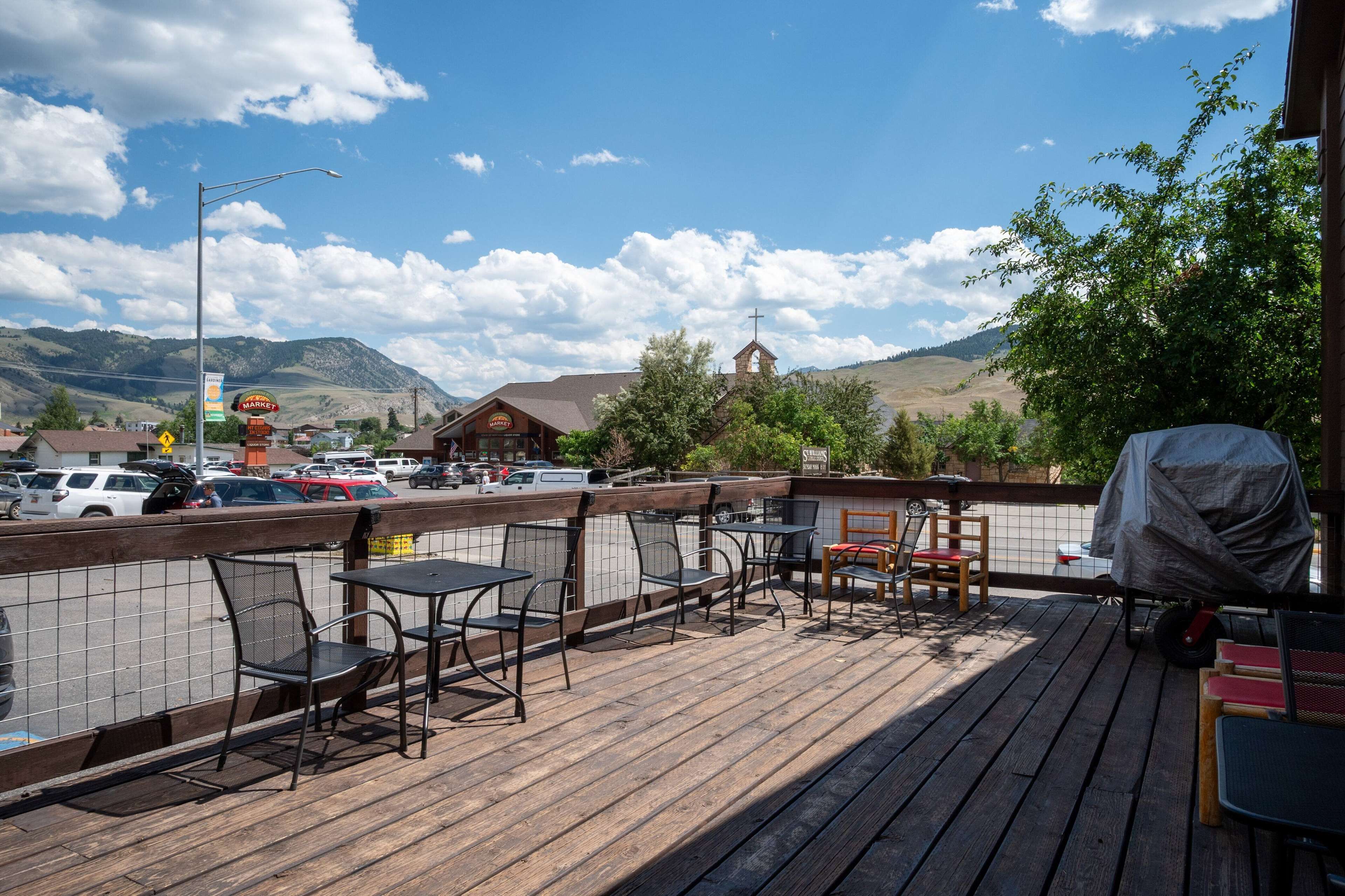 A deck with outdoor seating, a view of a church, and a parking lot in the background.