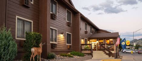 A two-story lodge with a wooden facade, a front entrance with steps, and a small American flag.