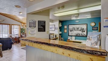 A reception area with a wooden counter, framed pictures, and a clock on the wall.