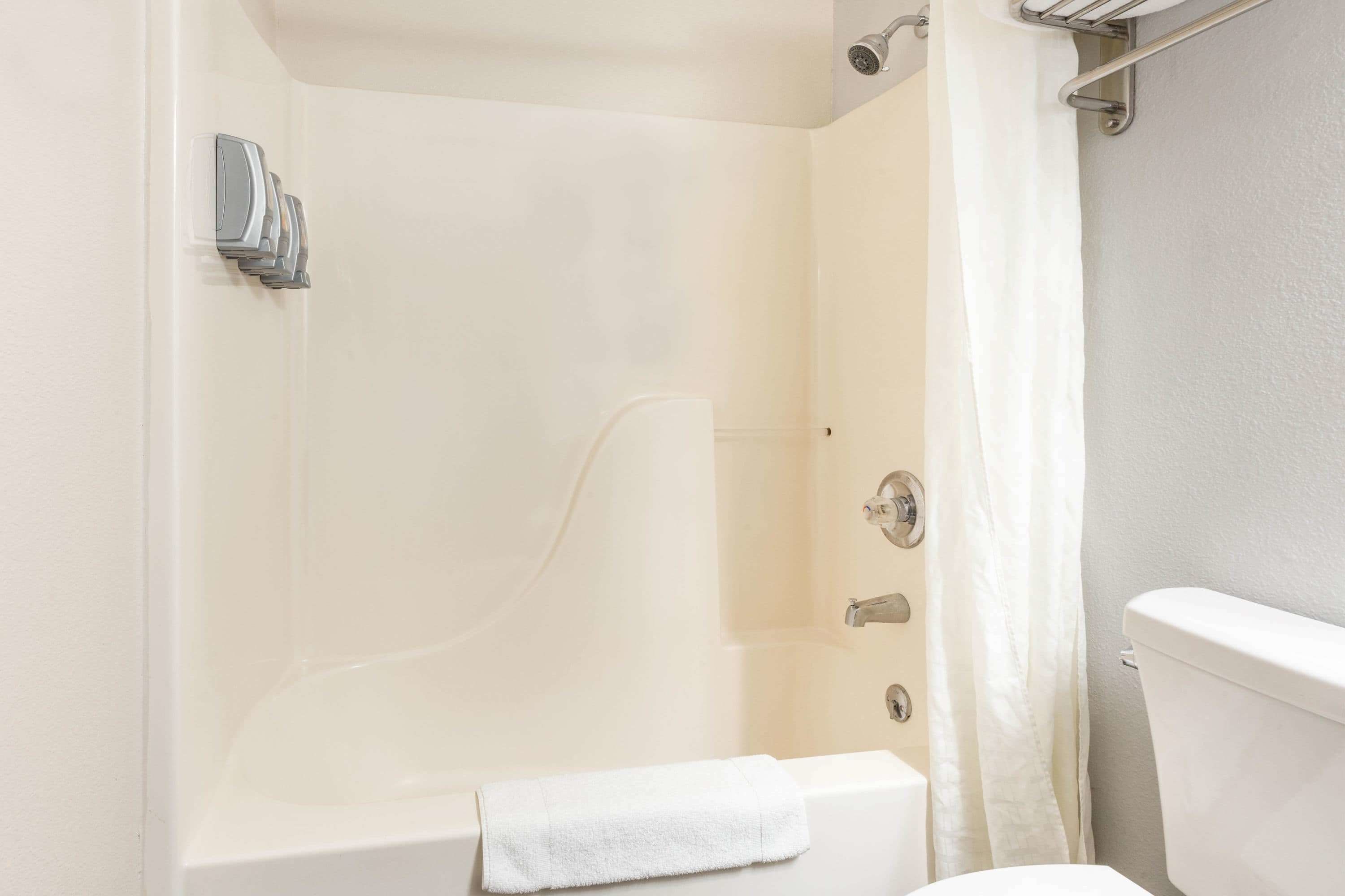 A bathroom with a bathtub, a toilet, and a shower curtain.
