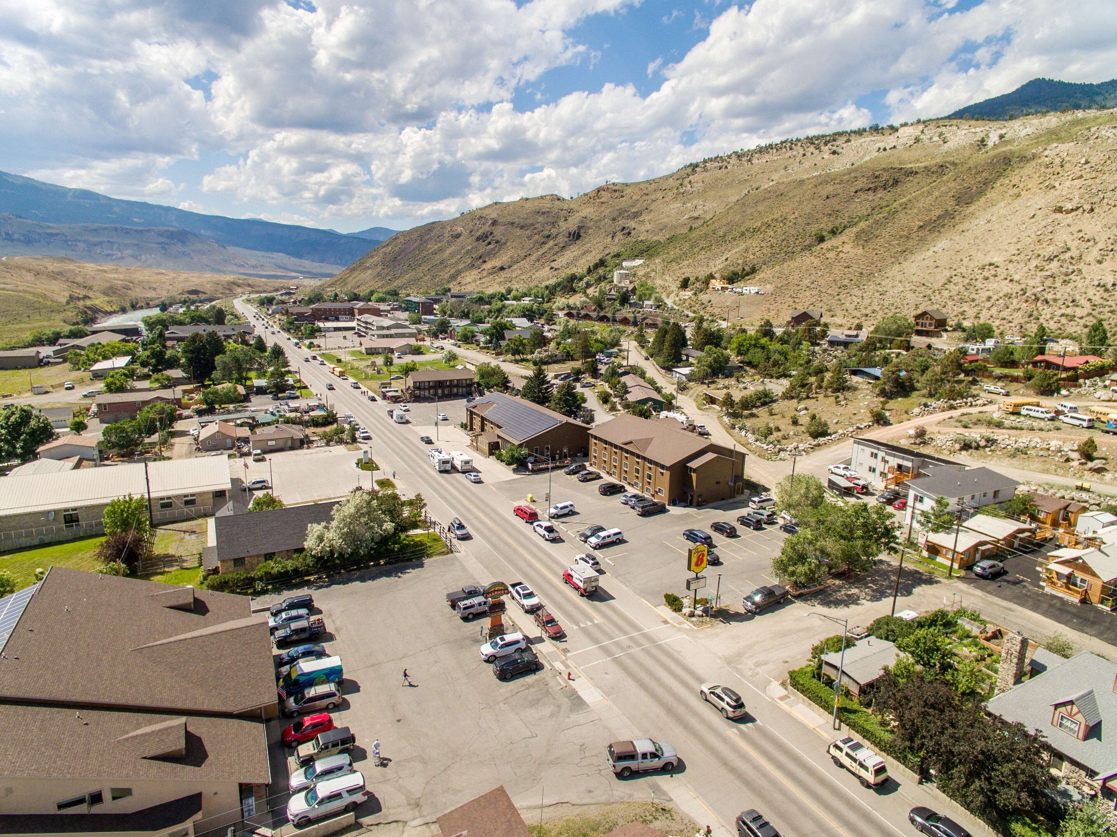 A town with a main road, buildings, and a mountainous backdrop.