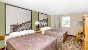 Habitación de hotel con dos camas, una mesita de noche de madera, una lámpara, una ventana con cortinas y un aire acondicionado instalado en la pared.