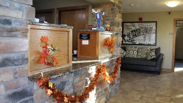 Un área de recepción con pared de piedra, armarios de madera, mostrador de check-in, un sofá y un cartel de bienvenida enmarcado.