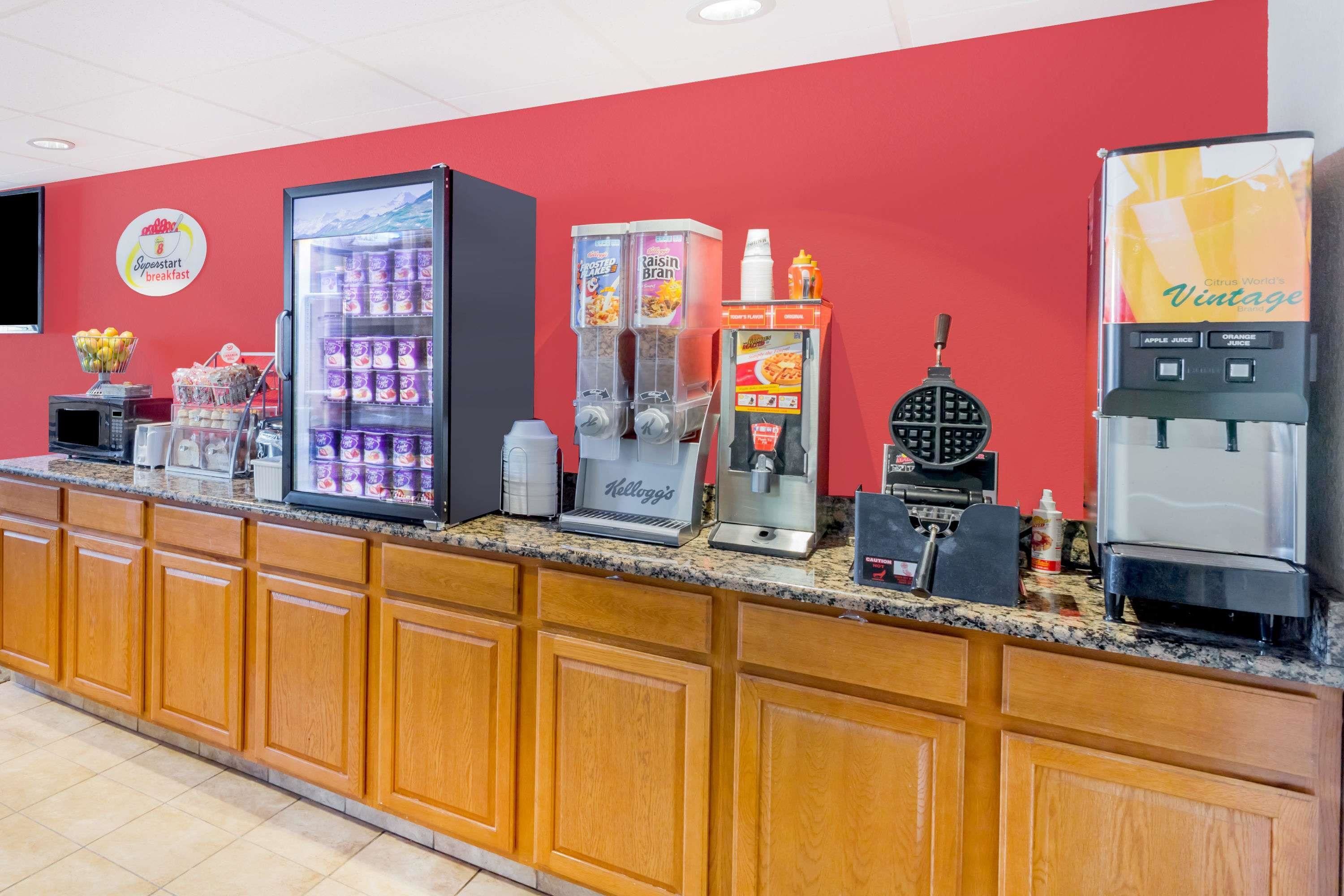 A breakfast bar with various beverage dispensers, including a refrigerator and a coffee machine.