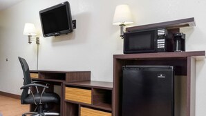 A hotel room with a desk, a black refrigerator, a microwave, a television, and two lamps. - Super 8 by Wyndham Zanesville (Zanesville)