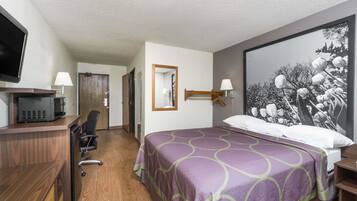 A hotel room with a bed, a desk with a computer, a chair, and a TV.