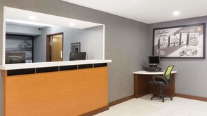 A reception area with a counter, a computer, and a desk with a chair. - Super 8 by Wyndham Zanesville (Zanesville)