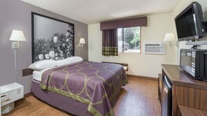 A hotel room with a bed, a television, a desk, and a window with curtains. - Super 8 by Wyndham Zanesville (Zanesville)