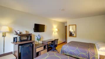 A hotel room with two beds, a desk with a computer, a microwave, and a refrigerator.