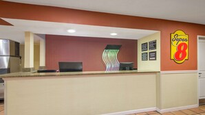 A hotel reception area with a counter, a refrigerator, and a wall with a 'Super 8' sign. - Super 8 by Wyndham Portales (Portales)