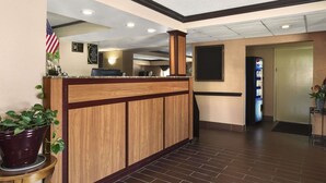 A reception area with a wooden reception desk, an American flag, and a Pepsi vending machine. - Super 8 by Wyndham Taylor/Detroit Area (Taylor)