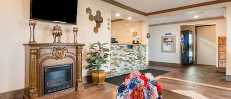A reception area with a fireplace, a television mounted on the wall, and a decorative plant.