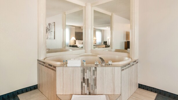 A modern bathroom with a large freestanding bathtub, a vanity with a mirror, and a tiled floor.