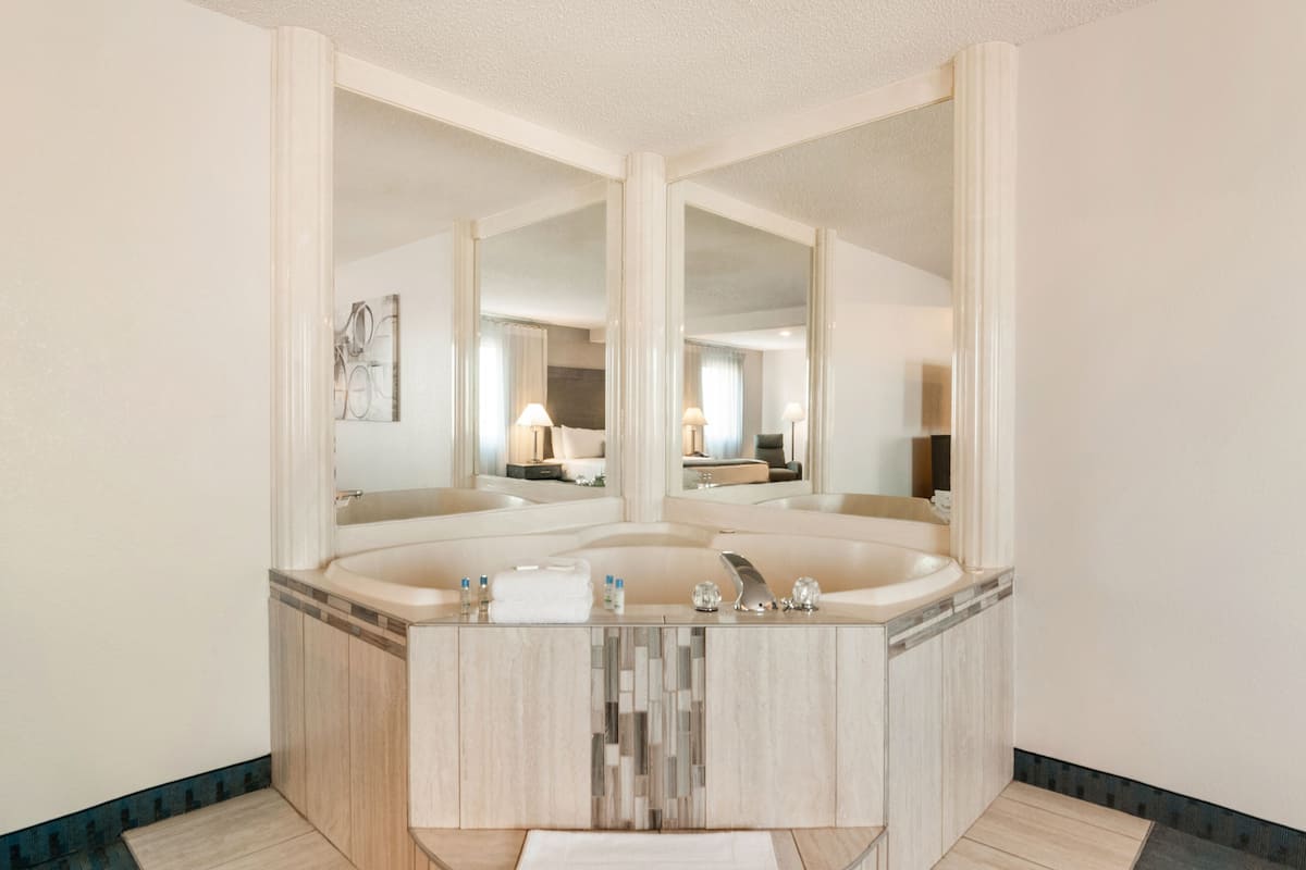A modern bathroom with a large freestanding bathtub, a vanity with a mirror, and a tiled floor.