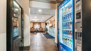 A hotel lobby with a Pepsi refrigerator, a seating area with a sofa and chairs, and a reception desk.