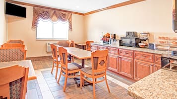 Una cocina con armarios de madera, encimera de granito y comedor con sillas y mesa de madera.