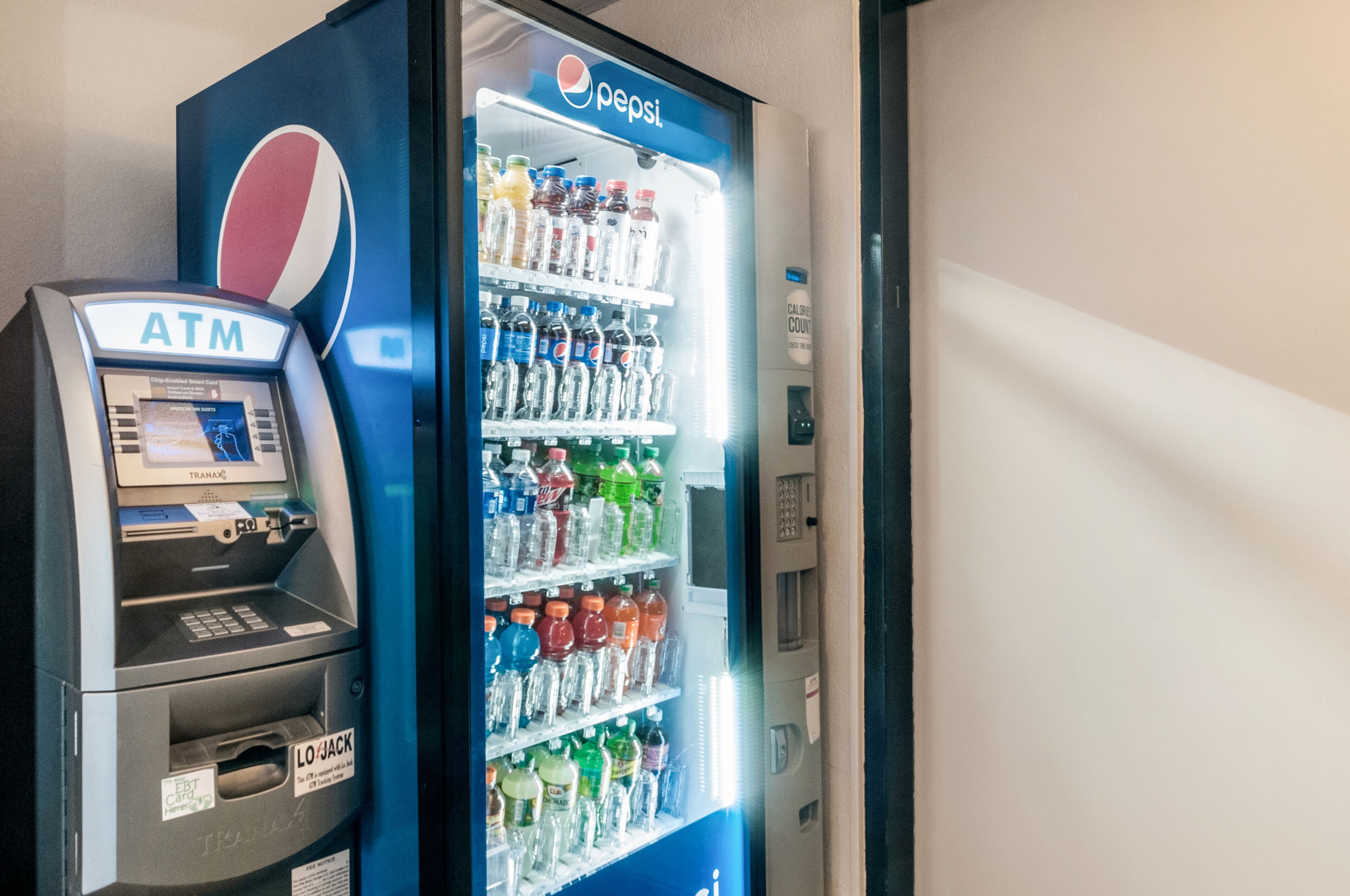 Un cajero automático y un refrigerador de Pepsi con diversas bebidas.