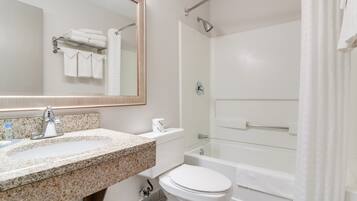 A modern bathroom with a granite sink, white toilet, and a walk-in shower.
