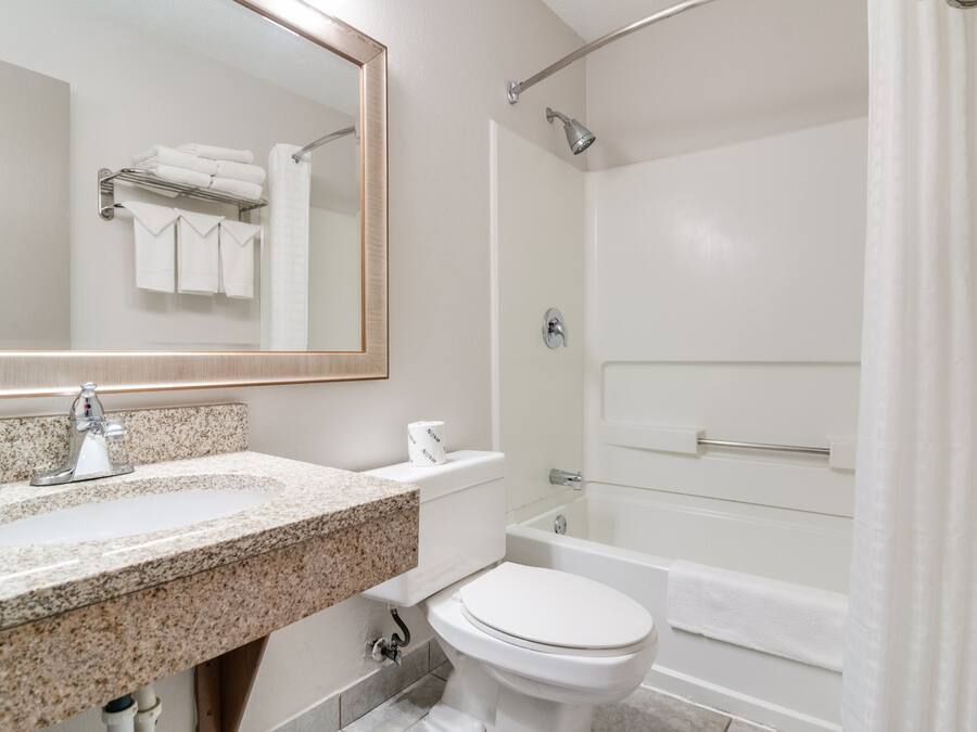 A modern bathroom with a granite sink, white toilet, and a walk-in shower.