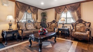 A traditional living room with ornate furniture, a floral centerpiece on the coffee table, and a large plant in the corner.
