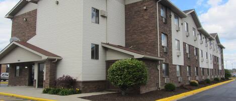 A multi-story hotel with a flat roof, brick and siding exterior, and a parking lot with yellow lines.