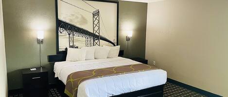 Habitación de hotel con una cama grande, dos mesitas de noche y una obra de arte colgada en la pared que representa un puente.