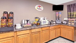 A breakfast bar with coffee makers, a microwave, and a fruit display. - Super 8 by Wyndham Wyoming/Grand Rapids Area (Wyoming)