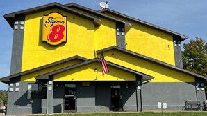 A Super 8 hotel with a yellow facade, a prominent 'Super 8' sign, an American flag, and a 'Lobby' sign. - Super 8 by Wyndham Marietta (Marietta)