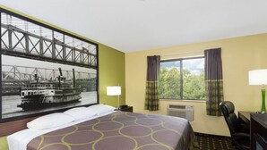 A hotel room with a bed, a desk, a chair, a window with curtains, a lamp, and a wall-mounted air conditioner. - Super 8 by Wyndham Marietta (Marietta)