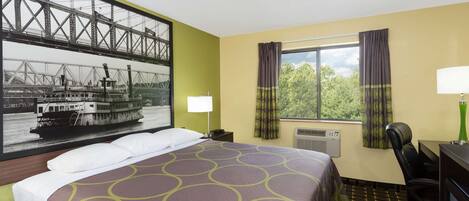 A hotel room with a bed, a desk, a chair, a window with curtains, a lamp, and a wall-mounted air conditioner.