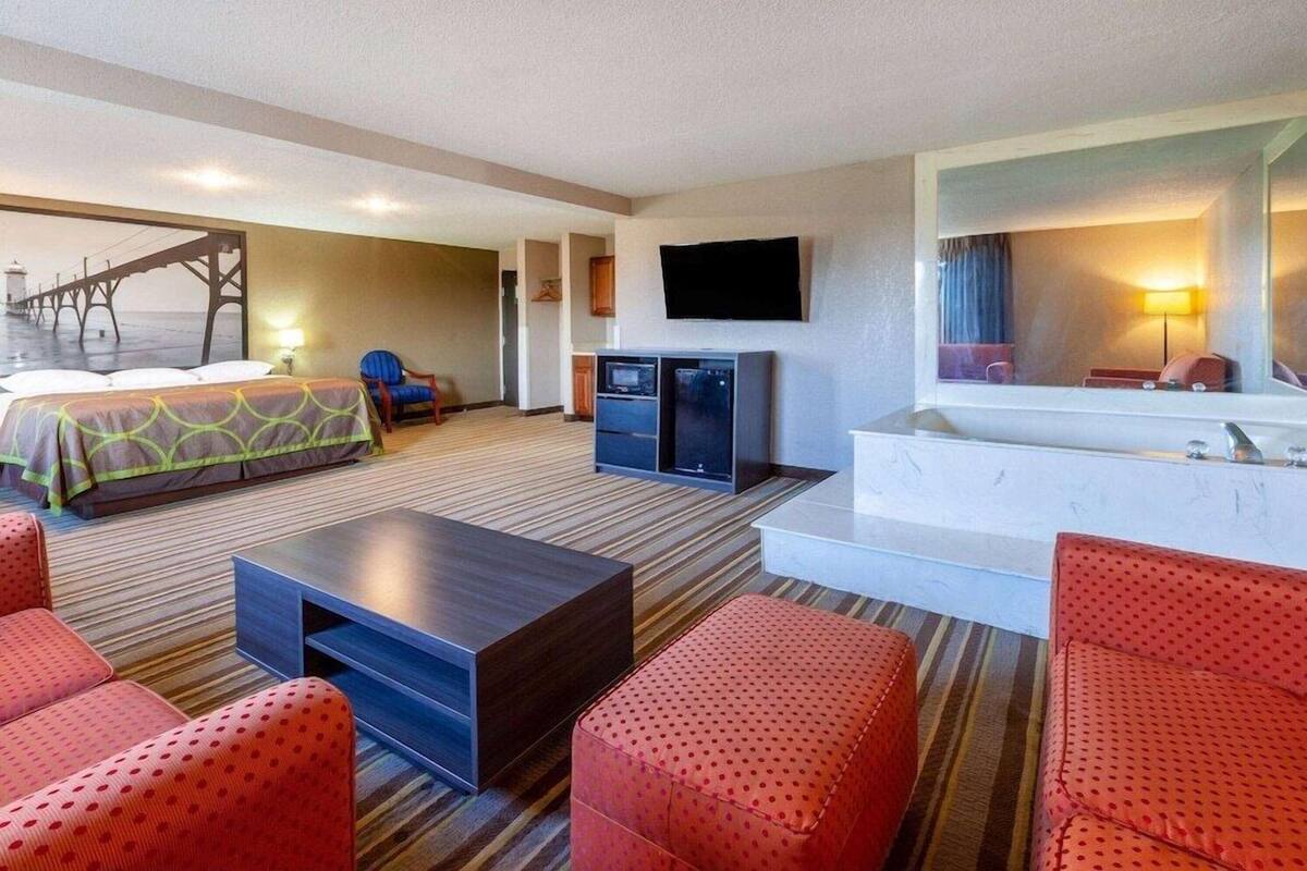 Hotelkamer met een bed, televisie, bureau, stoel, bank, een klein kitchenette en een badkamer.