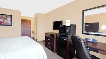 Una habitación de hotel con una cama, un escritorio con computadora, un microondas y un televisor.
