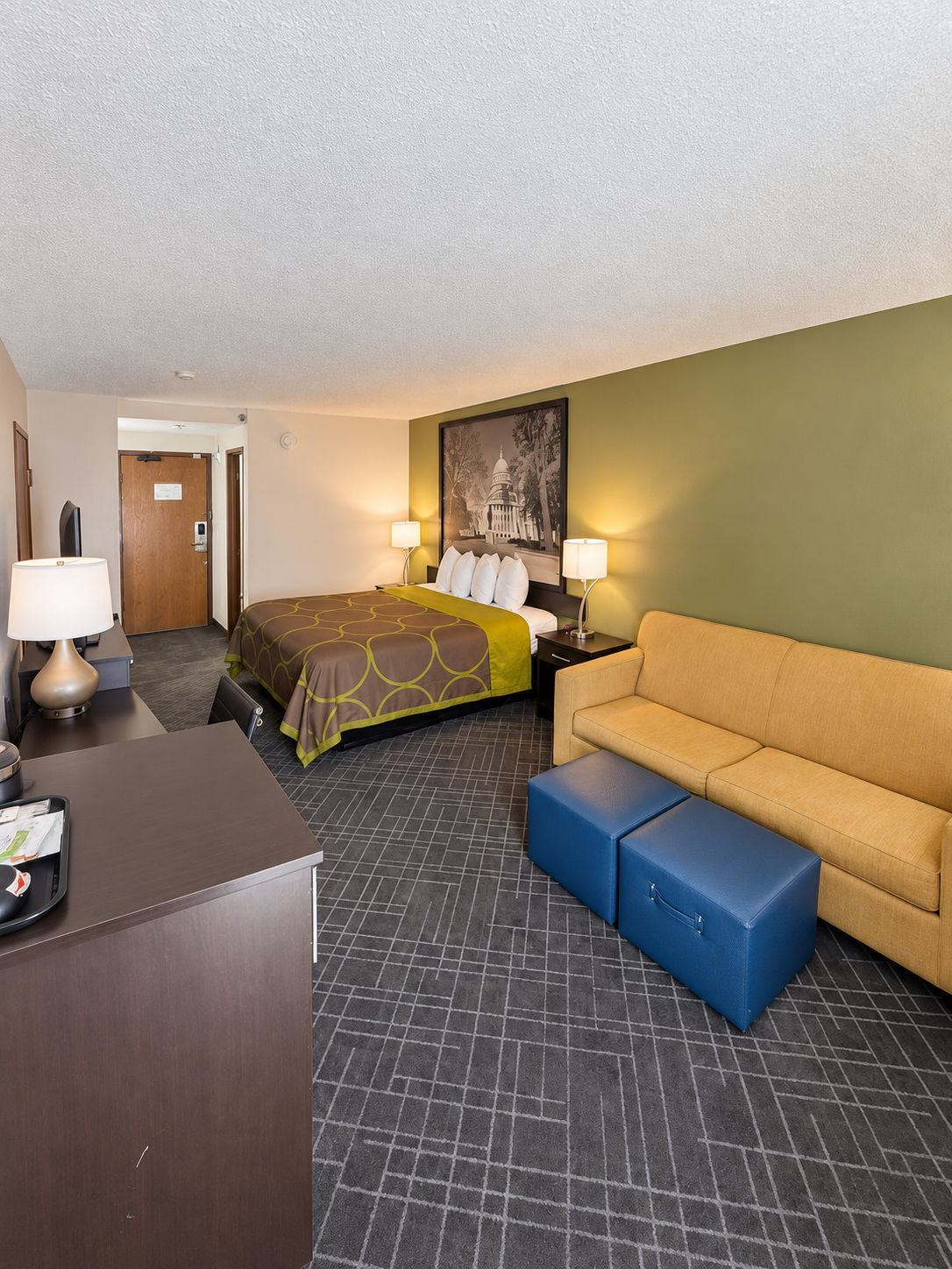 Una habitación de hotel con cama, sofá, escritorio y cesto de basura.
