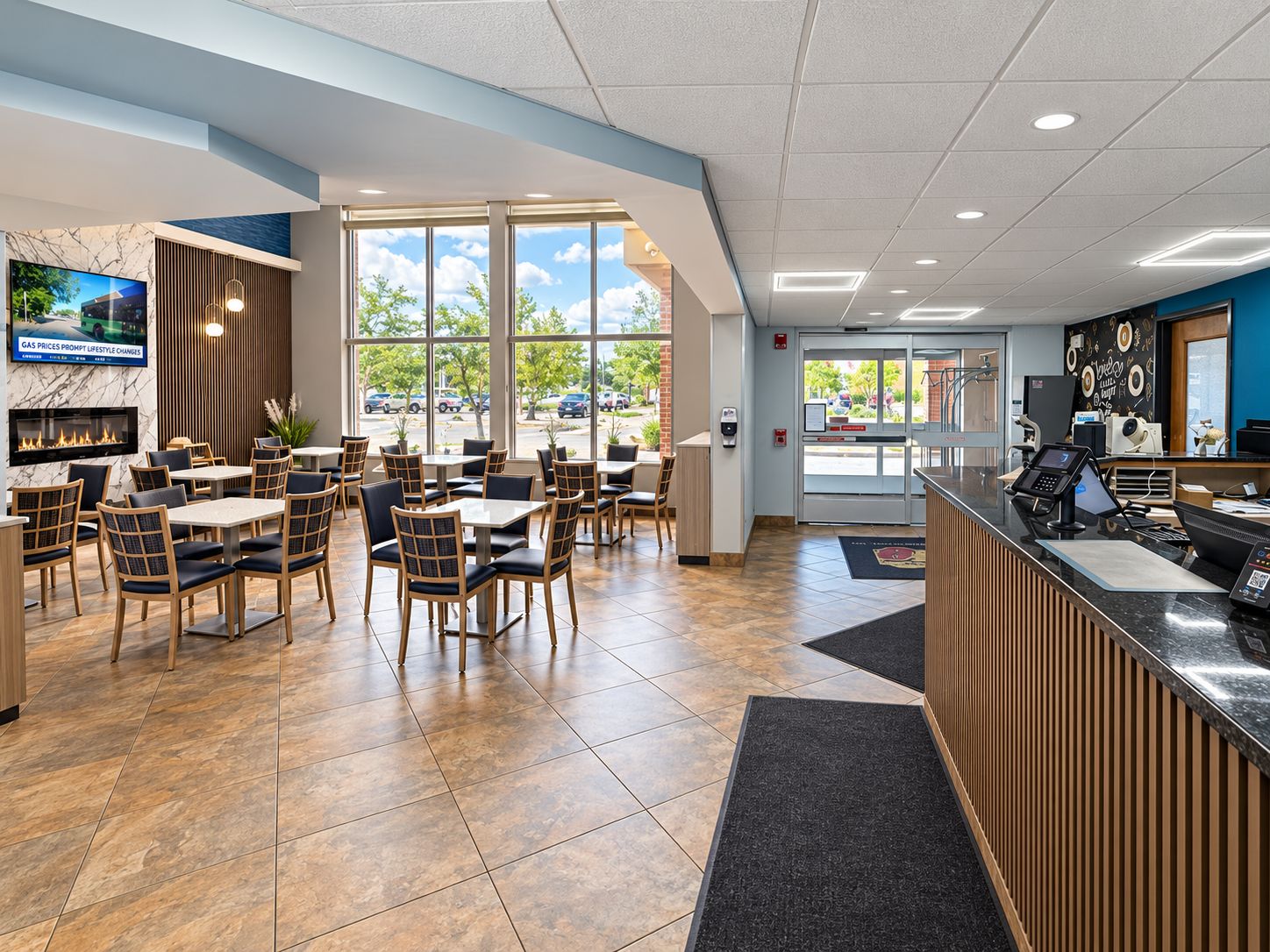 A restaurant with outdoor seating, a fireplace, and a reception area with a counter and digital kiosk.
