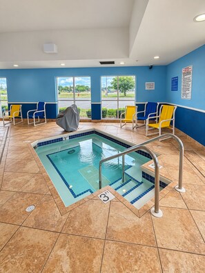A pool area with a 3ft depth, tiled flooring, and chairs along the walls. - Super 8 by Wyndham Madison South (Madison)
