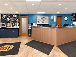 A hotel reception area with a coffee station, a clock, and a framed welcome sign.