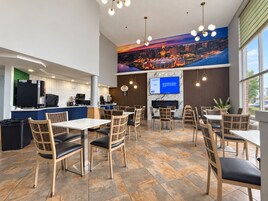 A restaurant with a cityscape mural, a counter with a coffee machine, and multiple seating areas with tables and chairs.