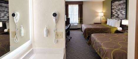 A hotel room with a large bathroom sink, two beds with matching headboards, a mirror, and a painting on the wall.