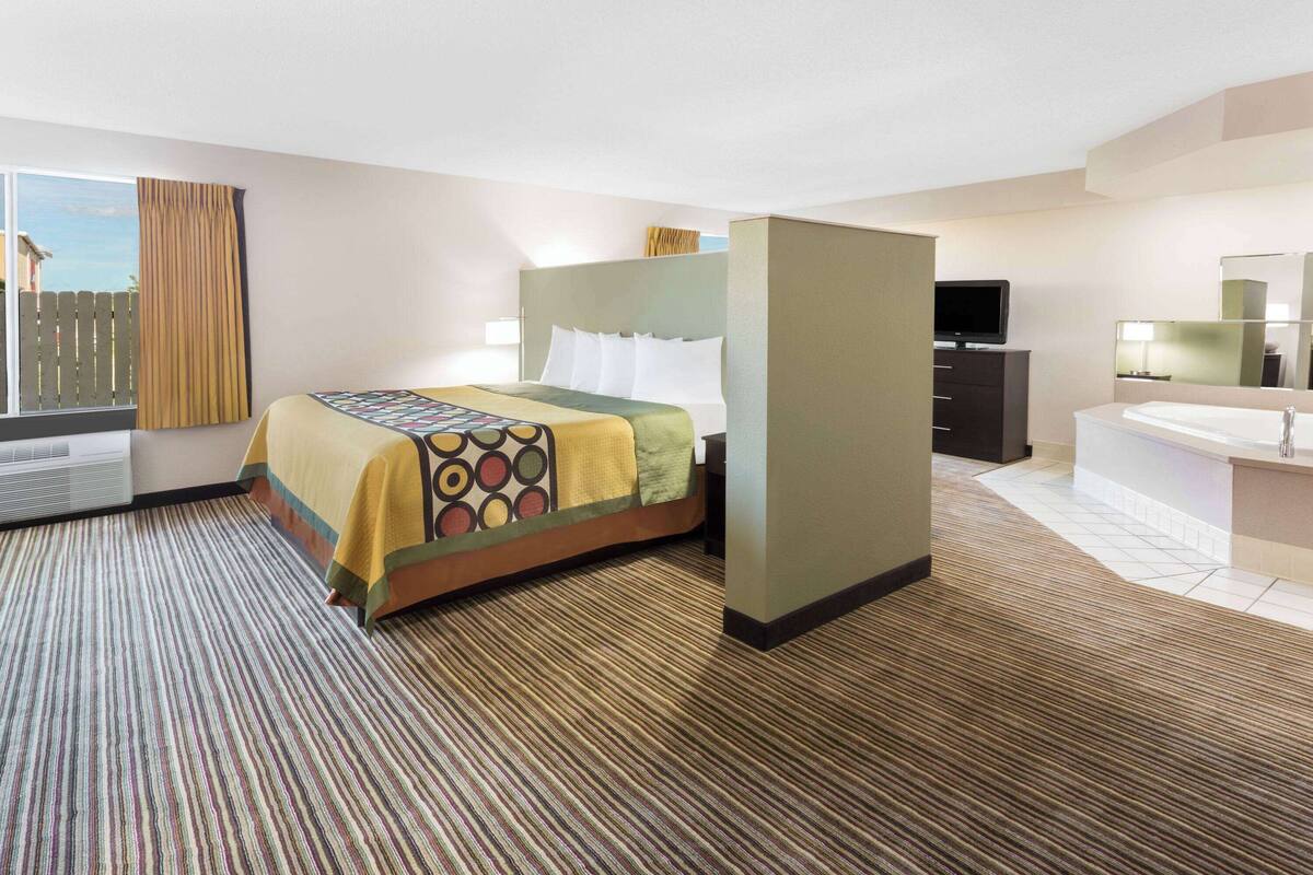A hotel room with a bed, a desk, a TV, and a bathroom.