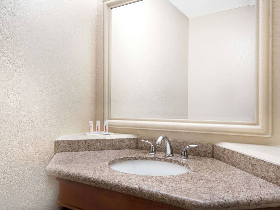 Un baño con encimera de granito, dos lavamanos y un espejo grande.