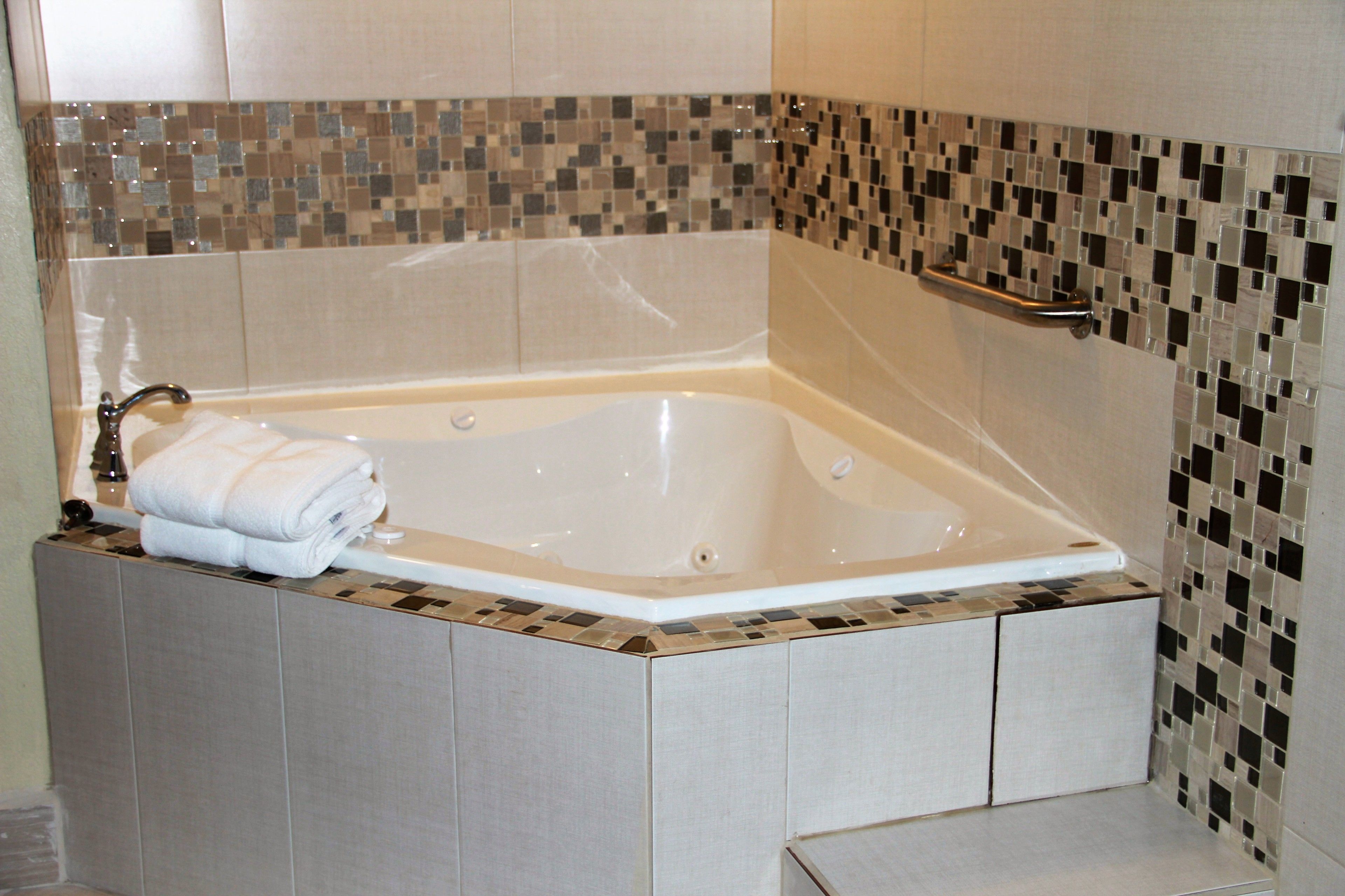 A modern bathroom with a freestanding bathtub, a towel rack, and mosaic tile walls.